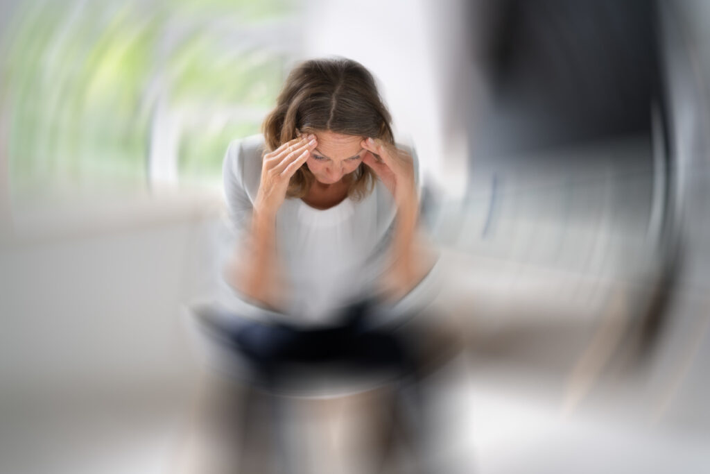 Frau hält sich den Kopf, weil ihr schwindelig ist